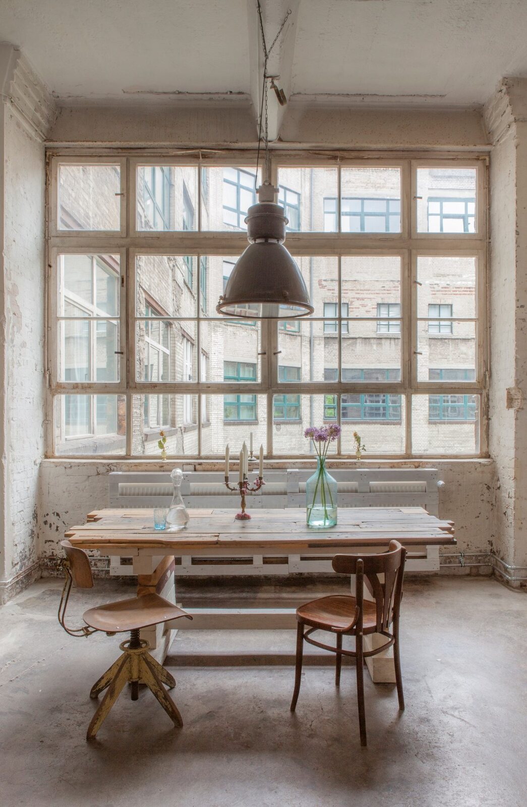 Tisch vor großem Fabrikfenster mit Blick in den Hof